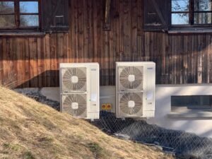 Deux unités de climatisation extérieures installées contre un mur en bois, assurant une efficacité énergétique optimale