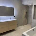 Salle de bain moderne rénovée avec des carreaux gris, une douche à l'italienne et des équipements sanitaires élégants.