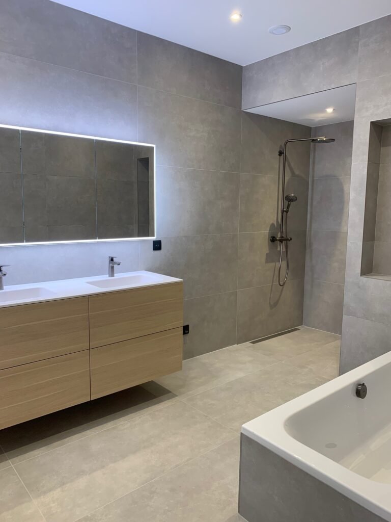 Salle de bain moderne rénovée avec des carreaux gris, une douche à l'italienne et des équipements sanitaires élégants.