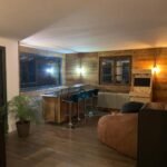 Intérieur d'un salon rénové avec des finitions en bois, un coin bar moderne et un poêle à bois.