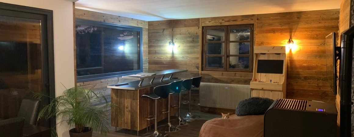 Intérieur d'un salon rénové avec des finitions en bois, un coin bar moderne et un poêle à bois.